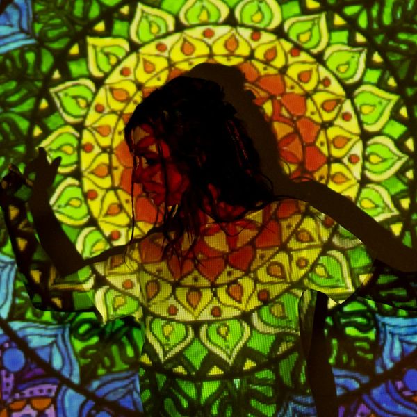 Woman performing a core-strengthening yoga pose, silhouette against a cyan background.